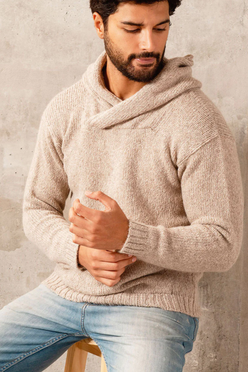 Man wearing a beige knitted sweater against a plain background