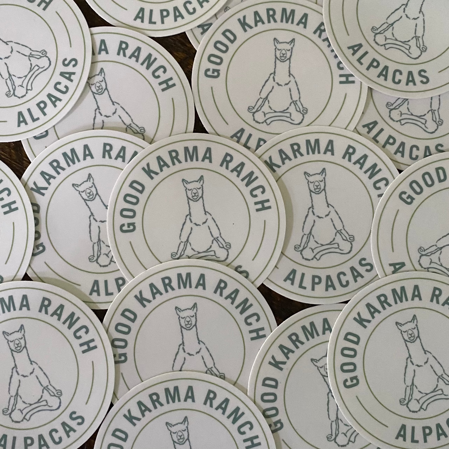 A collection of round white stickers with the Good Karma Ranch logo, featuring an alpaca, in black text.