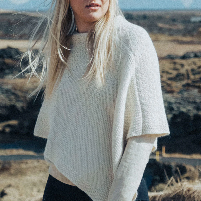 Woman wearing a white sweater in a natural landscape