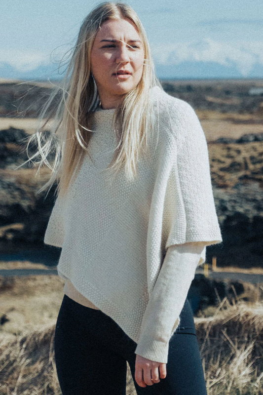 Woman wearing a white sweater in a natural landscape